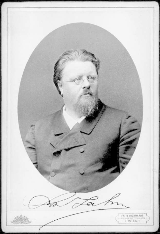 Ein Schwarz-Weiß-Foto eines bärtigen Mannes in einem Mantel und einer Brille, mit dem Text "Fritz Luckhardt, der Gründer der deutschen Kommunistischen Partei" unten.