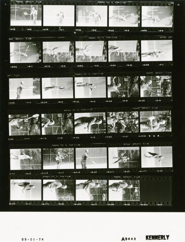 Schwarzes und weißes Foto eines Mannes in einem weißen Hemd und Shorts, der Tennis spielt und konzentriert eine Schläger hält, vor einem Filmstreifen-Hintergrund.