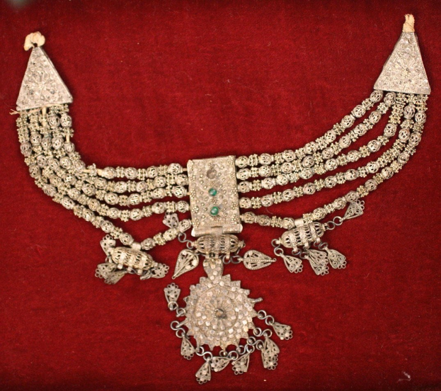 Eine Silberkette mit Smaragden und Diamanten auf einem roten Samtgrund.