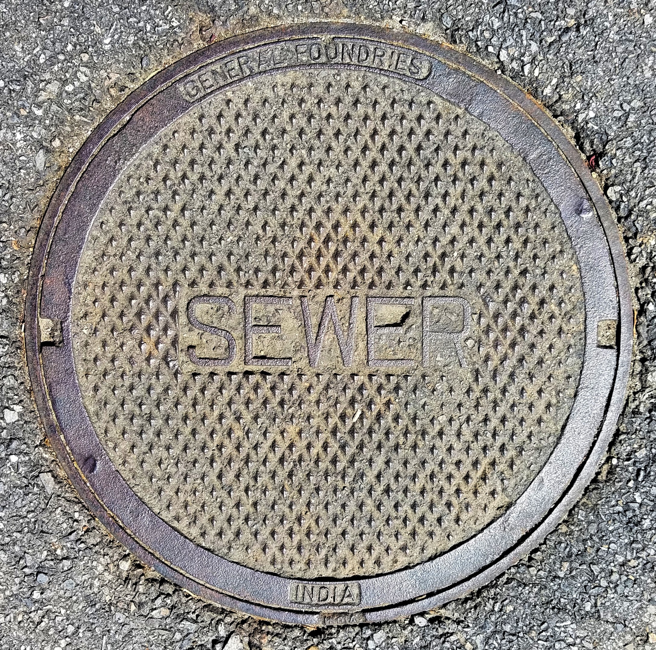 Metallschachtdeckel auf der Straße mit der Aufschrift 'Kanal'.