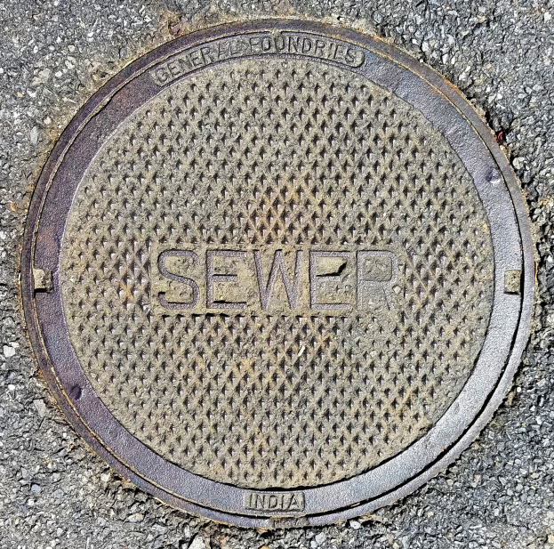 Metallschachtdeckel auf der Straße mit der Aufschrift 'Kanal'.