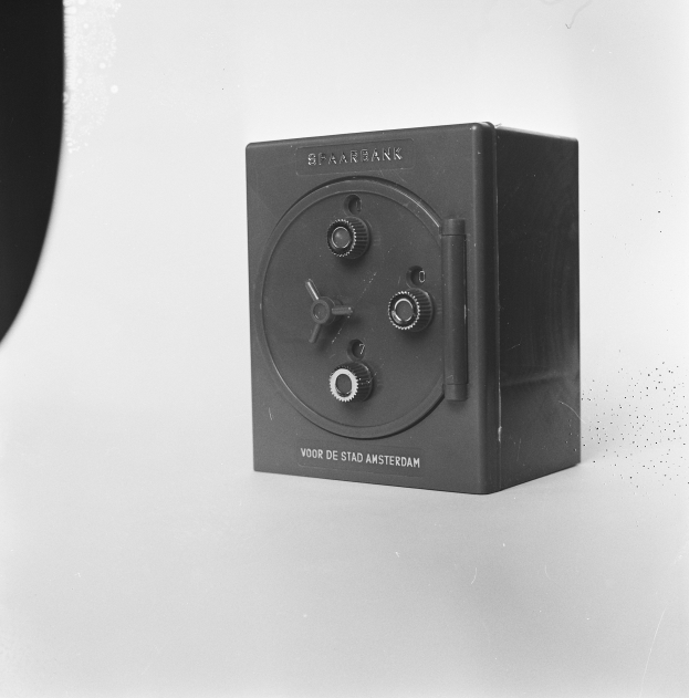 Ein Schwarz-Weiß-Foto eines rechteckigen Safe auf einer weißen Oberfläche, mit einem Griff oben, einem Schloss an der Vorderseite und einem Schlüsselloch in der Mitte.