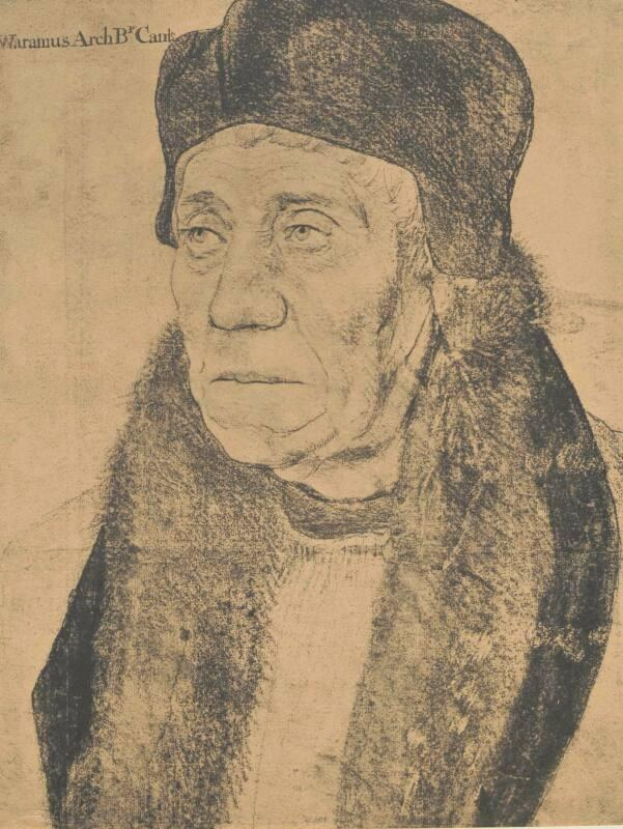 Eine ältere Frau mit grauen Haaren, die einen schwarzen Hut und einen Pelzmantel trägt, hält die Hände vor der Brust zusammen und schaut zur Seite mit einem sanften Gesichtsausdruck.