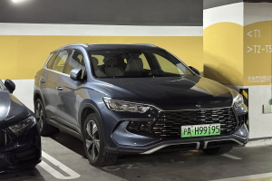 Zwei Autos nebeneinander in einer Tiefgarage geparkt, mit einer Wand und einer Deckenleuchte im Hintergrund und einer Tafel mit Text auf der rechten Seite, die auf Tests in China hinweist.