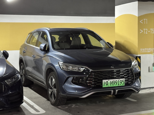 Zwei Autos nebeneinander in einer Tiefgarage geparkt, mit einer Wand und einer Deckenleuchte im Hintergrund und einer Tafel mit Text auf der rechten Seite, die auf Tests in China hinweist.