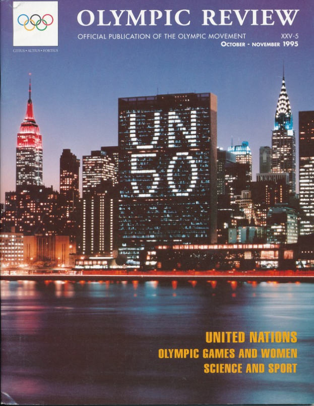Ein Buch mit dem Titel "Olympic Review Official Publication of the Olympic Movement" liegt auf einer flachen Oberfläche und zeigt auf seinem Cover eine Stadtlandschaft mit Gebäuden, Lichtern und Wasser, sowie den Text "United Nations Olympic Games and Women Science and Sport"