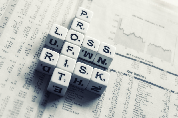 Crossword puzzle with the words "loss, risk, and risk" on a newspaper filled with financial text and numbers.