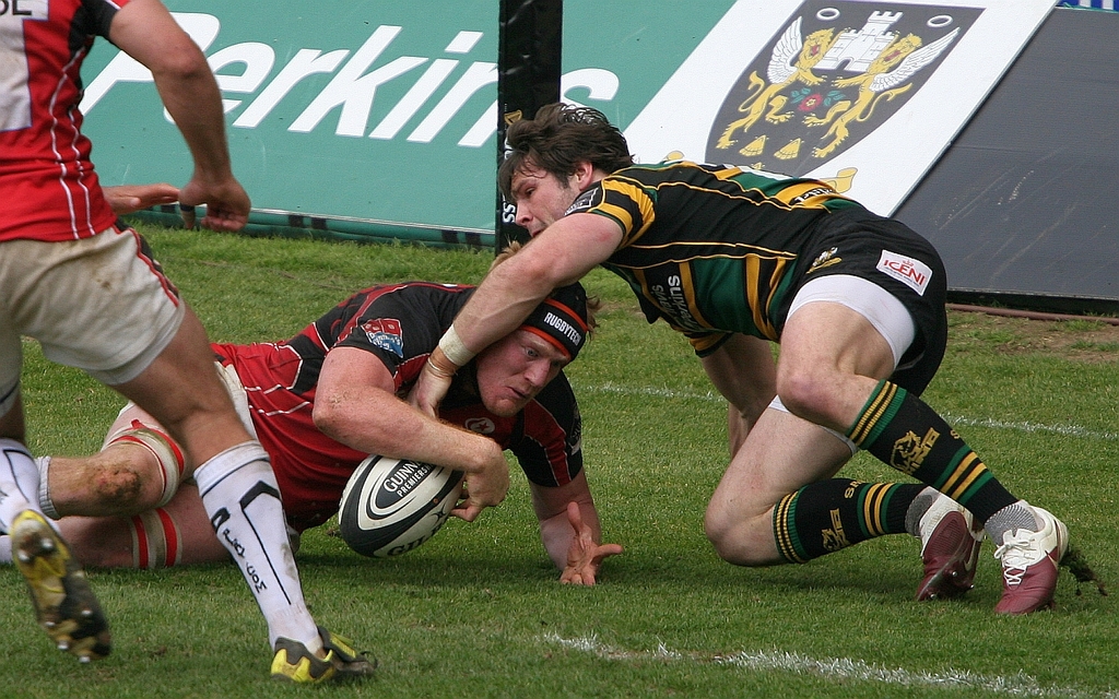 Eine Gruppe von Menschen auf dem Boden mit einem Rugbyball spielend.