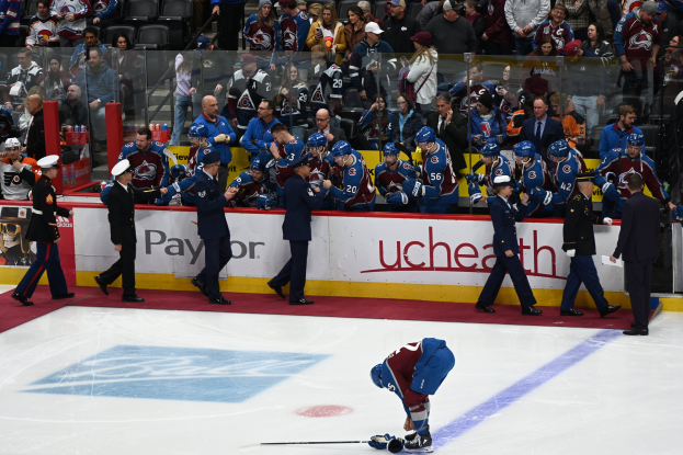 Hockeyspieler auf dem Eis umgeben von Teamkollegen und Gegnern, mit Zuschauern im Hintergrund während eines Spiels von Colorado Avalanche gegen San Jose Sharks am 3/24/15.
