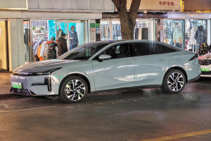 Ein Mitsubishi Lancer EV Elektroauto auf einer Straße bei Nacht geparkt, umgeben von Gebäuden, Geschäften, Schaufensterpuppen, Schildern und Lichtern.