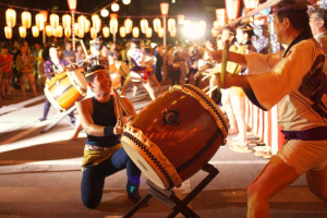 Männer, die Trommeln auf einem Festival mit Lichtern darüber spielen.