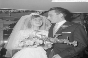 Ein Schwarz-Weiß-Foto eines Brautpaares, das zusammen steht, die Braut hält einen Strauß Blumen.